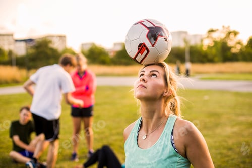 Preview: Sporty woman balancing soccer ball on head at park