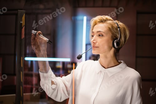 Preview: Caucasian female employee, managing working tasks, writing notes on glass transparent wall in office
