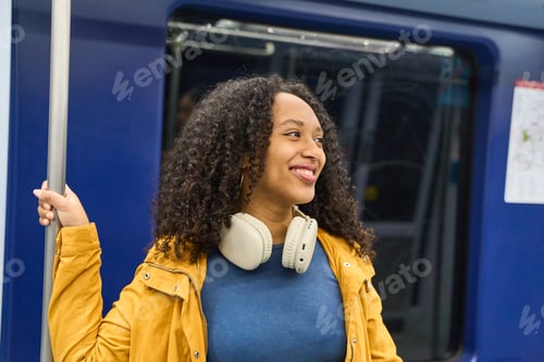 Preview: Young black woman smiling and holding a handrail on the subway train