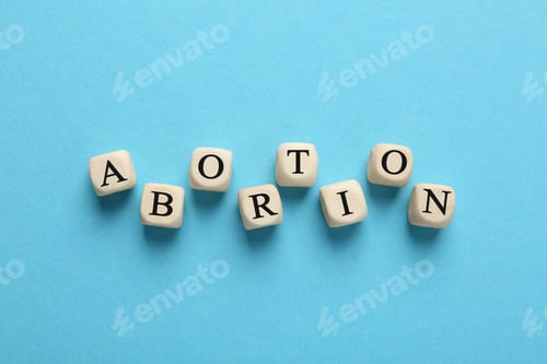 Preview: Word Abortion made of wooden cubes on light blue background, flat lay