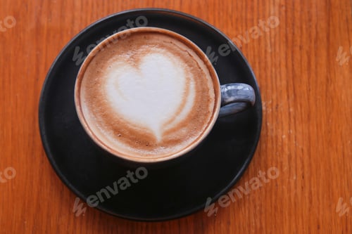 Preview: Warm cup of coffee with heart design on cream surface