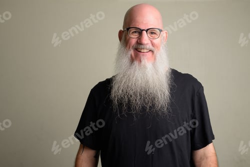 Preview: Happy mature bald man with long gray beard smiling and wearing eyeglasses