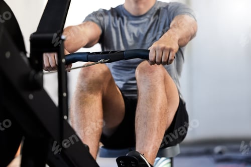 Preview: Cropped shot of an unrecognizable athletic man working out on a rowing machine in the gym