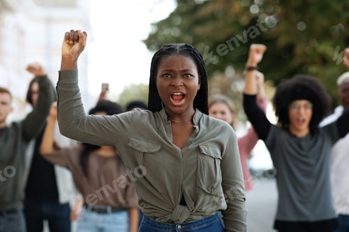 Preview: Black woman raising fist up, leading international group of demonstrators