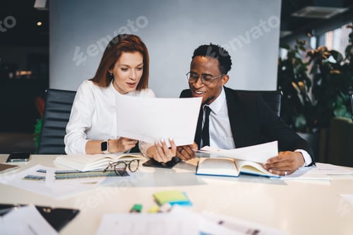 Preview: Happy multiracial colleagues analyzing papers in workspace