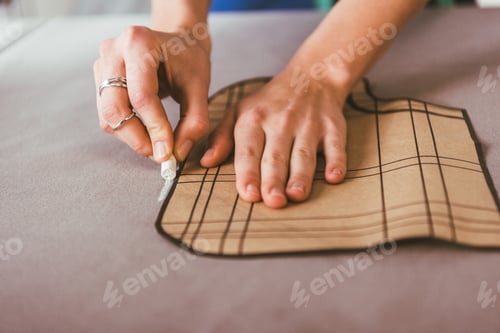 Preview: cropped image of dressmaker marking fabric with piece of chalk