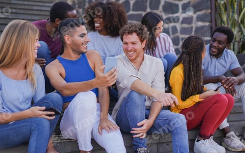 Preview: Group of multiracial young people hanging out together in the city while using mobile phones