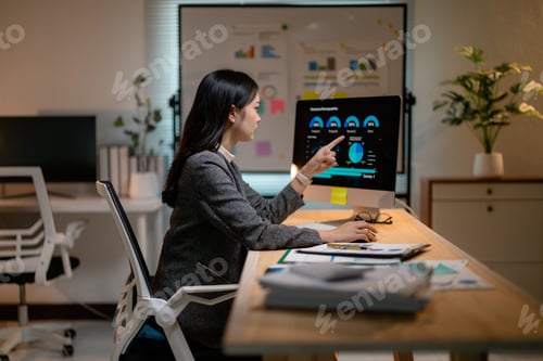 Preview: Asian businesswoman analyzing financial data on computer in office at night