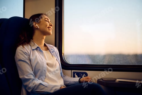 Preview: Happy woman with eyes closed enjoying her journey while traveling by train.