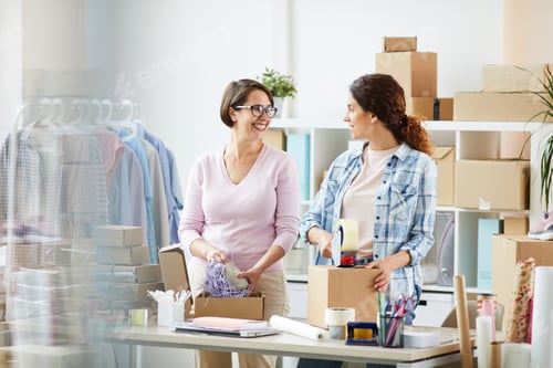 Preview: Happy young office managers preparing and packing orders of online clients