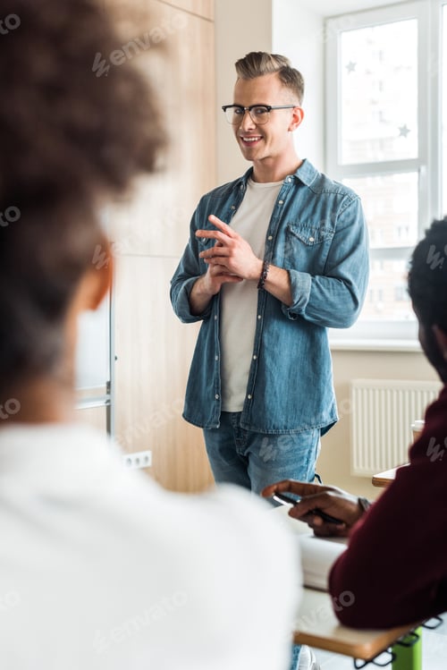 Preview: student in glasses and denim attire smiling in university