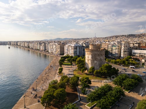 Preview: Aerial view of the White Tower in Thessaloniki, Greece, surrounded by lush greenery and the vibrant