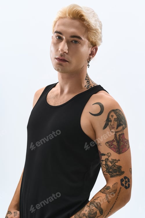 Preview: Stylish young man showcasing modern fashion with unique tattoos in a minimalist setting