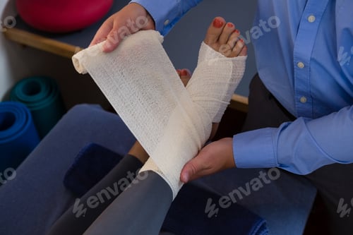 Preview: Physiotherapist putting bandage on injured feet of patient