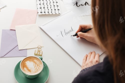 Preview: Beautiful photo of woman from backside sitting at white desk and writing notes isolated