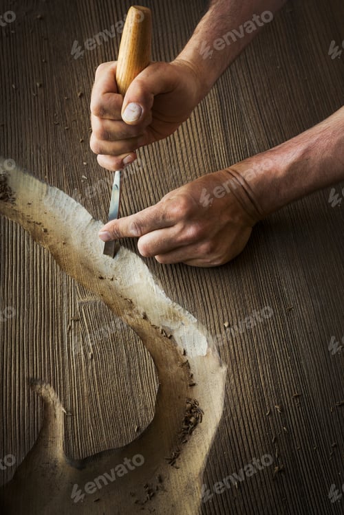 Preview: A craftsman using a chisel to carve out a deep groove in a piece of wood.