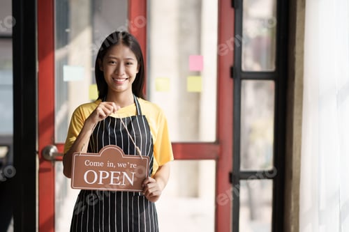 Preview: Small business owner smiling while turning the sign for the opening of the shop. Close up of woman