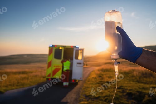 Preview: Paramedic holding IV drip against ambulance car of emergency medical servic