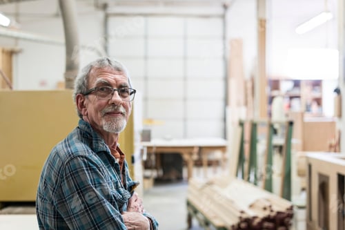 Preview: Portrait of a senior Caucasian carpenter in a large woodworking shop.