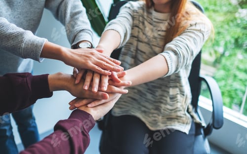 Preview: Closeup image of business team standing and joining their hands together in office