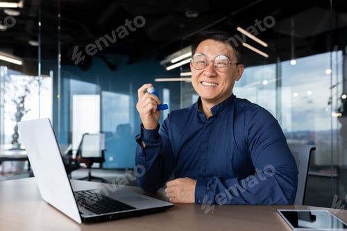 Preview: A young Asian businessman, freelancer, programmer works in the office at a laptop. He holds an