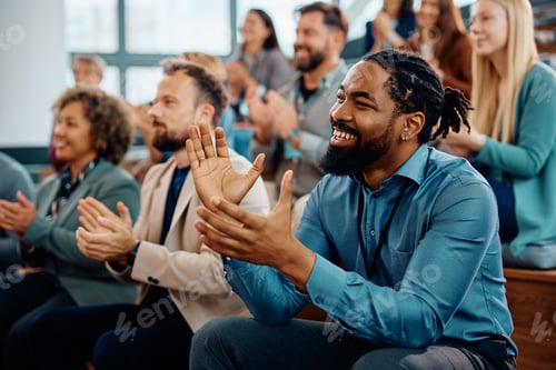 Preview: Happy black businessman applauding after successful conference in convention center.