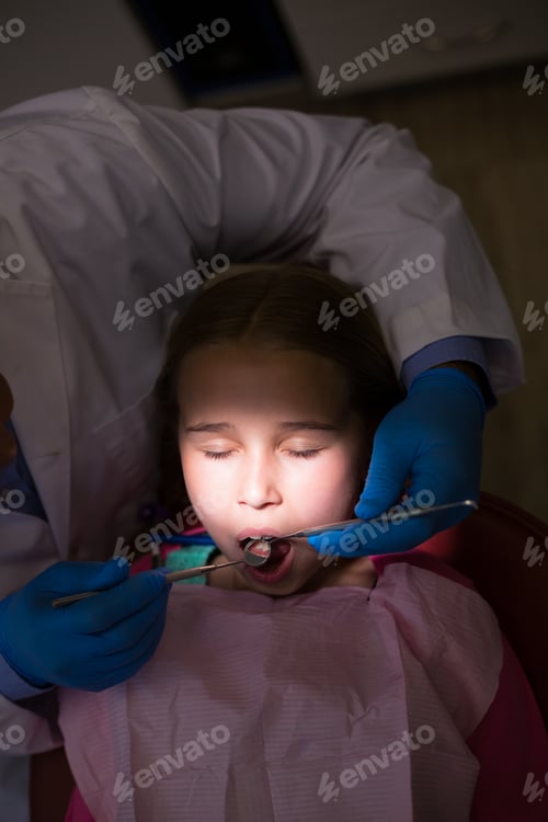 Preview: Dentist examining a young patient with tools