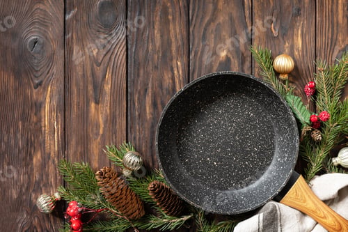 Preview: Empty cooking frying pan with tablecloth, Christmas tree and decor on wooden background.