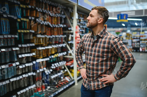 Preview: handsome young man shopping for tools at hardware store