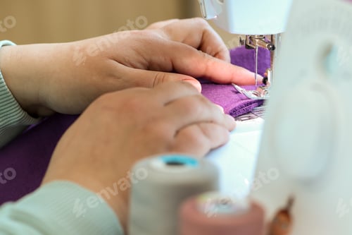 Preview: A woman sews children's clothes on a sewing machine. Hands of a seamstress. seamstress profession