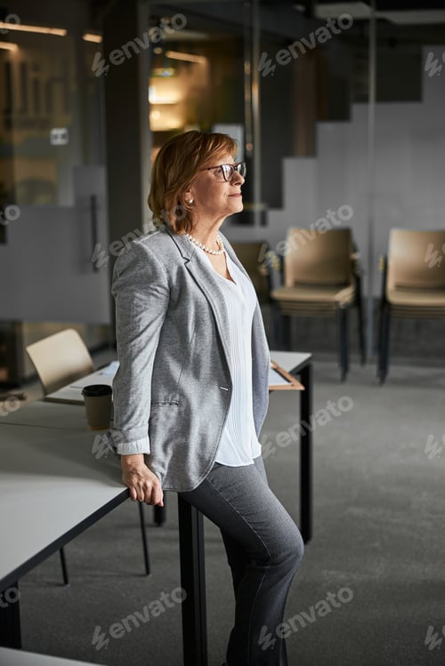 Preview: Mature businesswoman staring in a window of her office