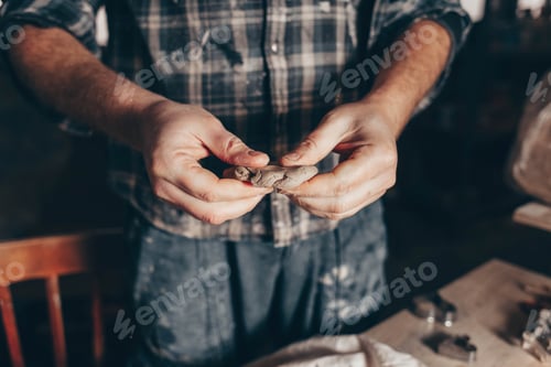 Preview: Potter kneads a piece of clay in his hand