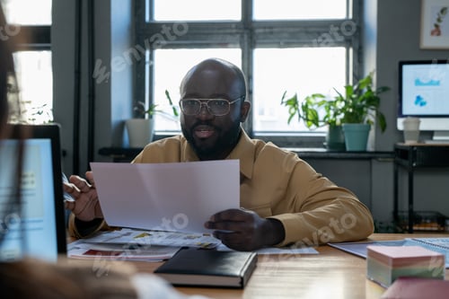 Preview: Confident African-American economist with paper explaining financial data
