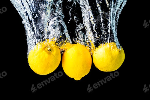 Preview: Lemons splash into water and sinking on black background.