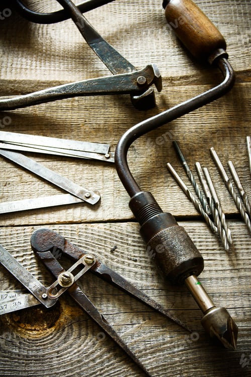 Preview: Old drill, compasses, ruler and drills on a wooden background.