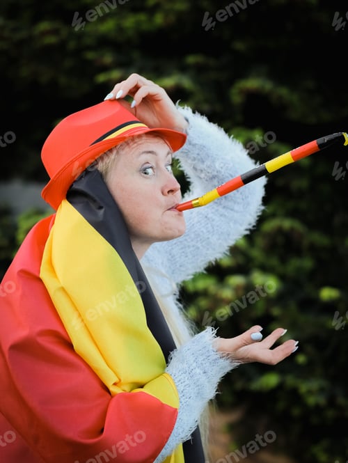 Preview: Caucasian woman holding a Belgian flag and blowing a whistle celebrating independence day