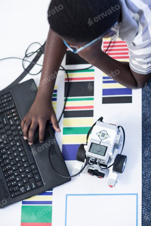 Preview: Schoolboy with laptop in robotics class testing vehicle on test track