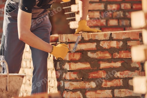 Preview: Busy with brick wall. Construction worker in uniform and safety equipment have job on building