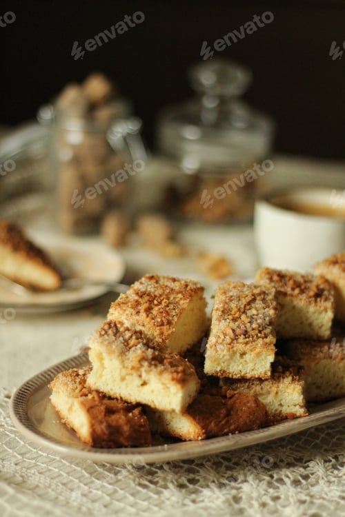 Preview: Cookies with nuts and sugar lie on a dish on the table next to a cup of coffee