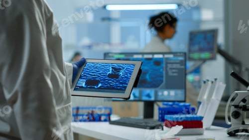 Preview: Close up of scientist in lab coat working holding tablet