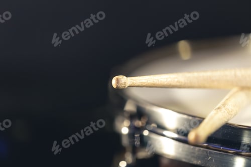 Preview: Close-up, snare drum and drumsticks on a dark background.