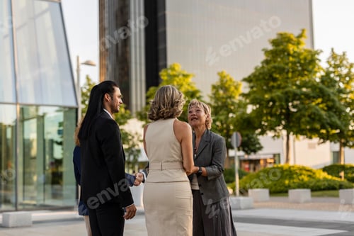 Preview: Business people shaking hands in front of modern office building