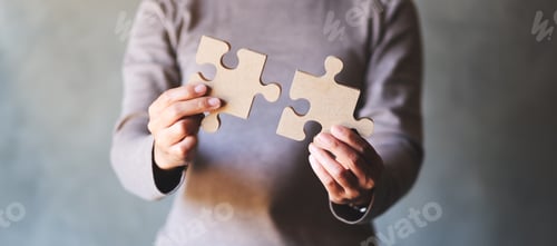 Preview: Closeup image of a woman holding and putting a piece of wooden jigsaw puzzle together