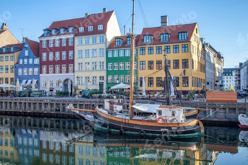 Preview: COPENHAGEN, DENMARK - MAY 6, 2018: boat and beautiful colorful buildings reflected in calm water of