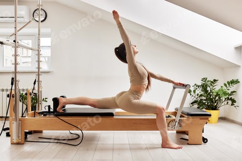 Preview: A young girl is doing Pilates on a reformer bed in a bright studio. A beautiful slender brunette in