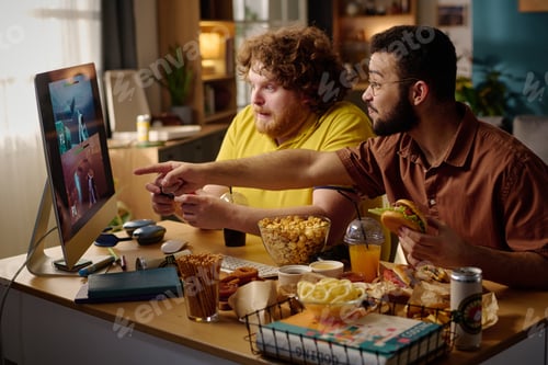Preview: Two Friends Gaming Together and Eating Snacks at Desk