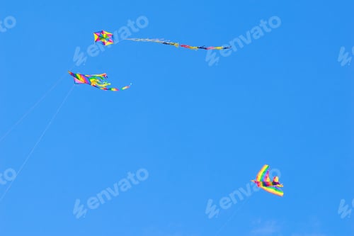 Preview: colorful kites in blue sky with small white clouds