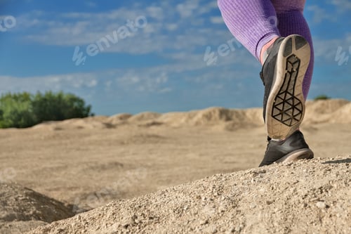 Preview: woman legs runs in purple leggings in black and gray sneakers copy space bottom view