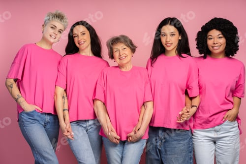Preview: Five smiling women holding hands wearing pink t-shirts for breast cancer awareness