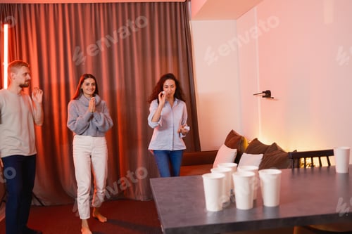 Preview: Friends Playing a Fun Game of Beer Pong in a Cozy Indoor Setting